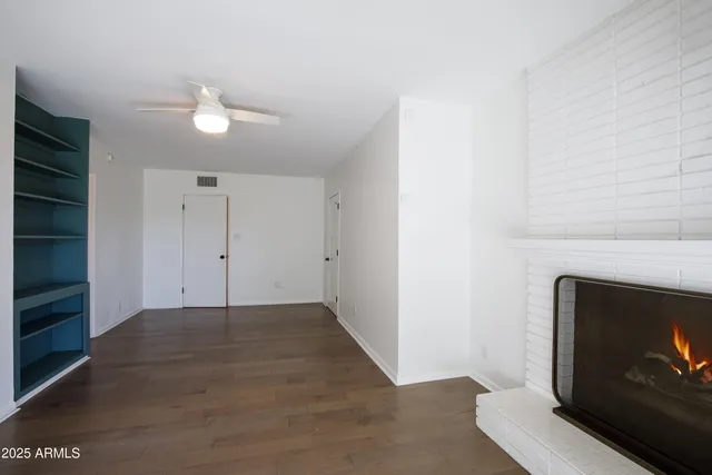 a view of an empty room with wooden floor and a fireplace