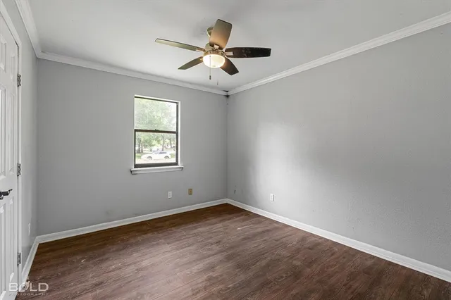 an empty room with wooden floor ceiling fan and windows