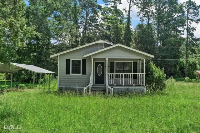 a view of house with a big yard and large trees