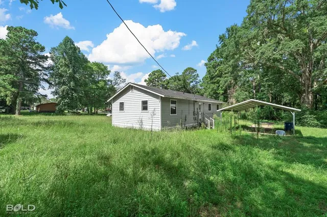 a backyard of a house with table and chairs plants and large tree