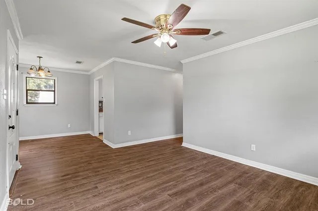 an empty room with wooden floor and ceiling fan
