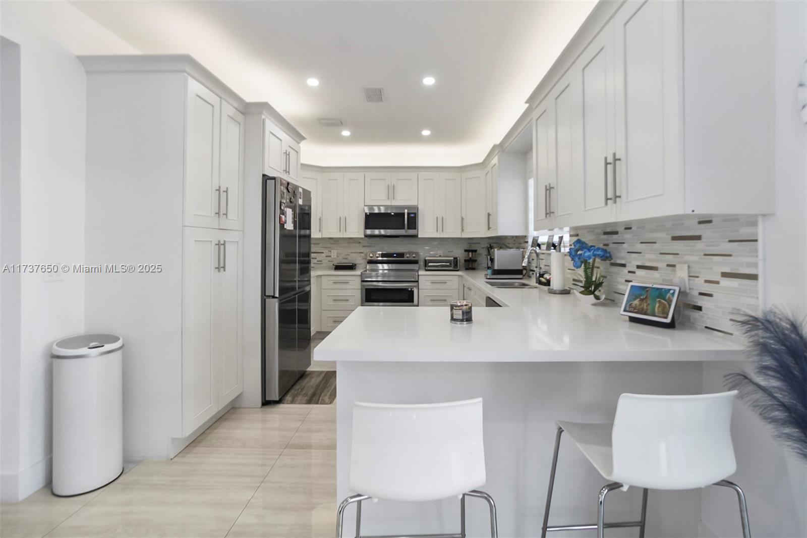 10290 Southwest 7th Terrace Sweetwater, FL 33174 - Photo 15 of 58 a kitchen with stainless steel appliances a sink a stove a refrigerator cabinets and chairs