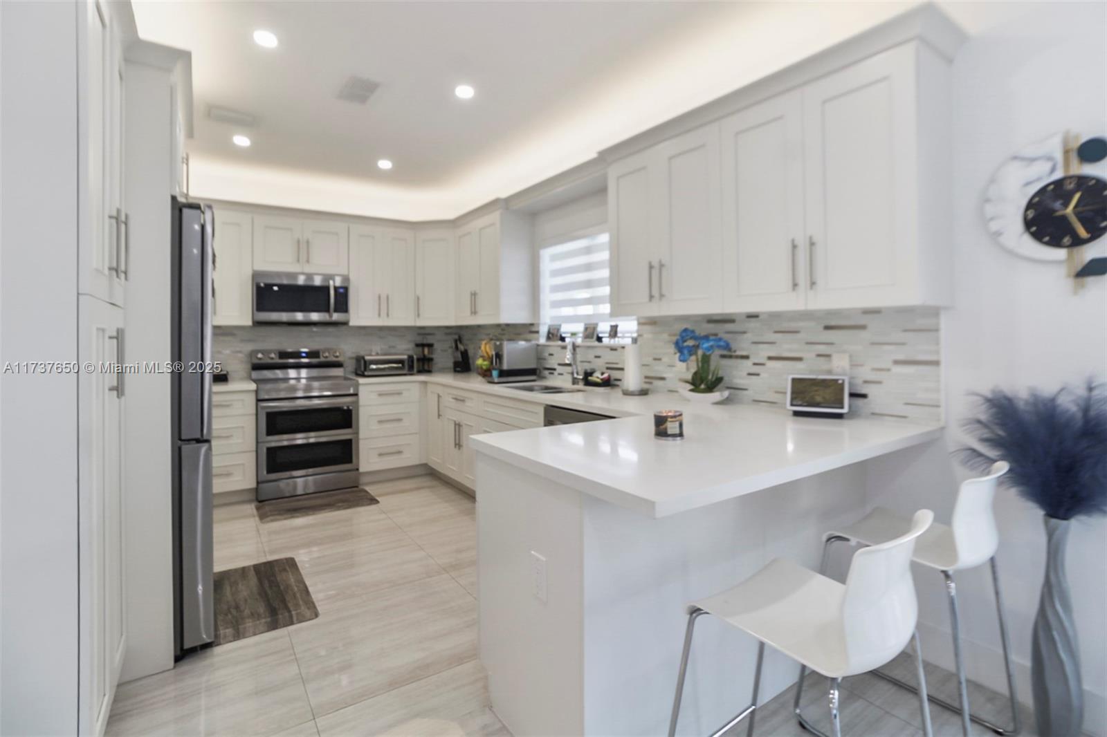 10290 Southwest 7th Terrace Sweetwater, FL 33174 - Photo 16 of 58 a kitchen with stainless steel appliances a sink a stove a refrigerator cabinets and a window
