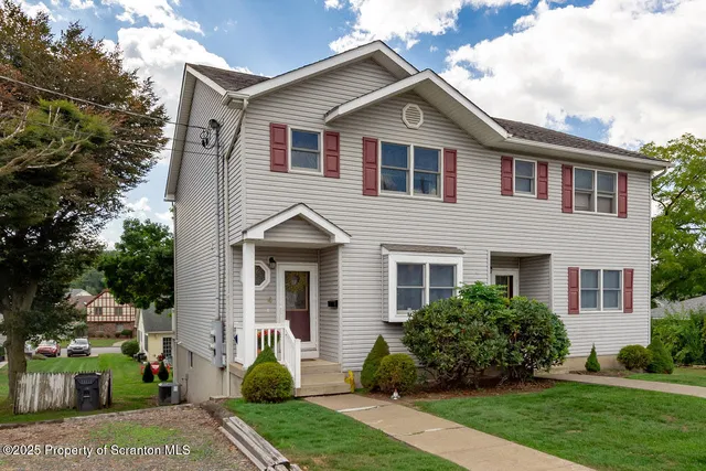 a front view of a house with a yard and potted plants