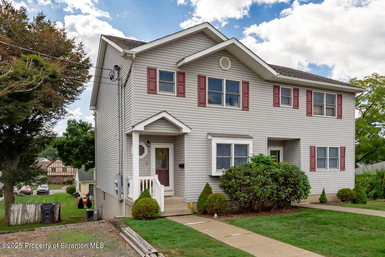 a front view of a house with a yard and potted plants