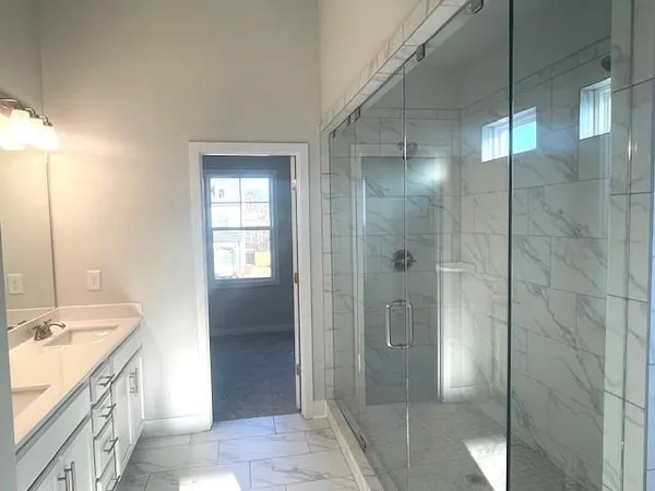 a spacious bathroom with a double vanity sink a mirror and a shower