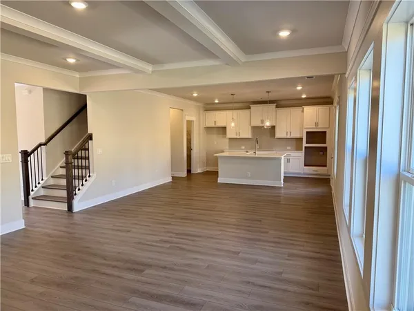 a view of kitchen and an empty room with wooden floor
