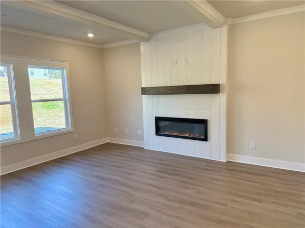 an empty room with wooden floor fireplace and windows