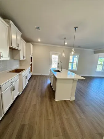 a large kitchen with granite countertop a large counter top a sink stainless steel appliances and cabinets