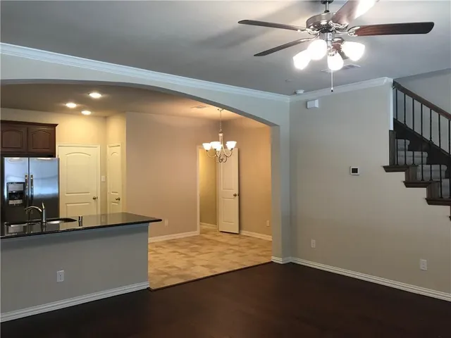 a view of a room with a chandelier fan and wooden floor