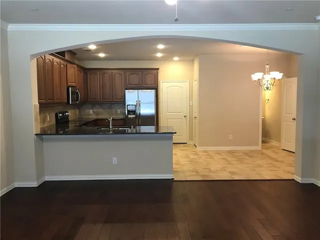 a kitchen with granite countertop a stove a sink and a refrigerator