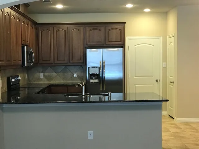 a kitchen with stainless steel appliances granite countertop a refrigerator and a sink
