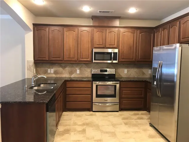 a kitchen with granite countertop a refrigerator and a stove top oven