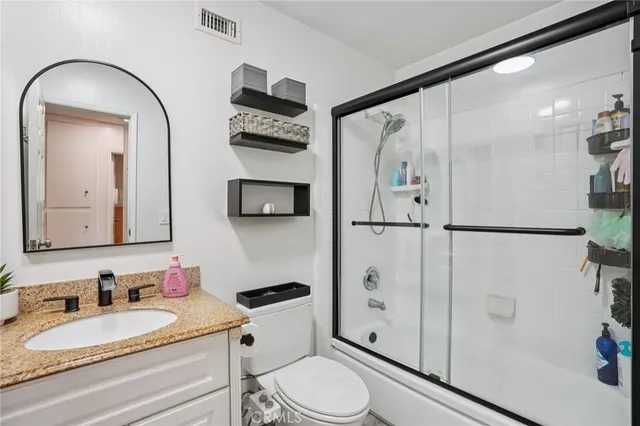 a bathroom with a granite countertop sink mirror vanity and toilet