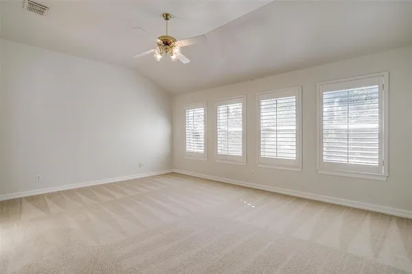 an empty room with chandelier fan and windows