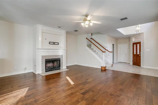 a view of an empty room with wooden floor fireplace and a window