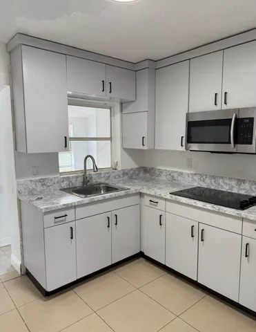 a kitchen with granite countertop white cabinets and a sink