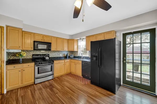 a kitchen with granite countertop wooden floors stainless steel appliances and window