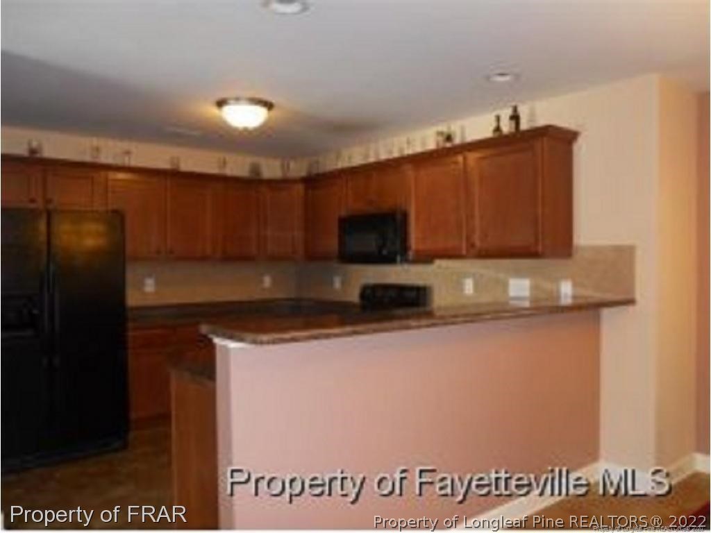 2165 Yellowbrick Road Fayetteville, NC 28314 - Photo 6 of 7 a kitchen with stainless steel appliances granite countertop a refrigerator a stove and a microwave with wooden floor