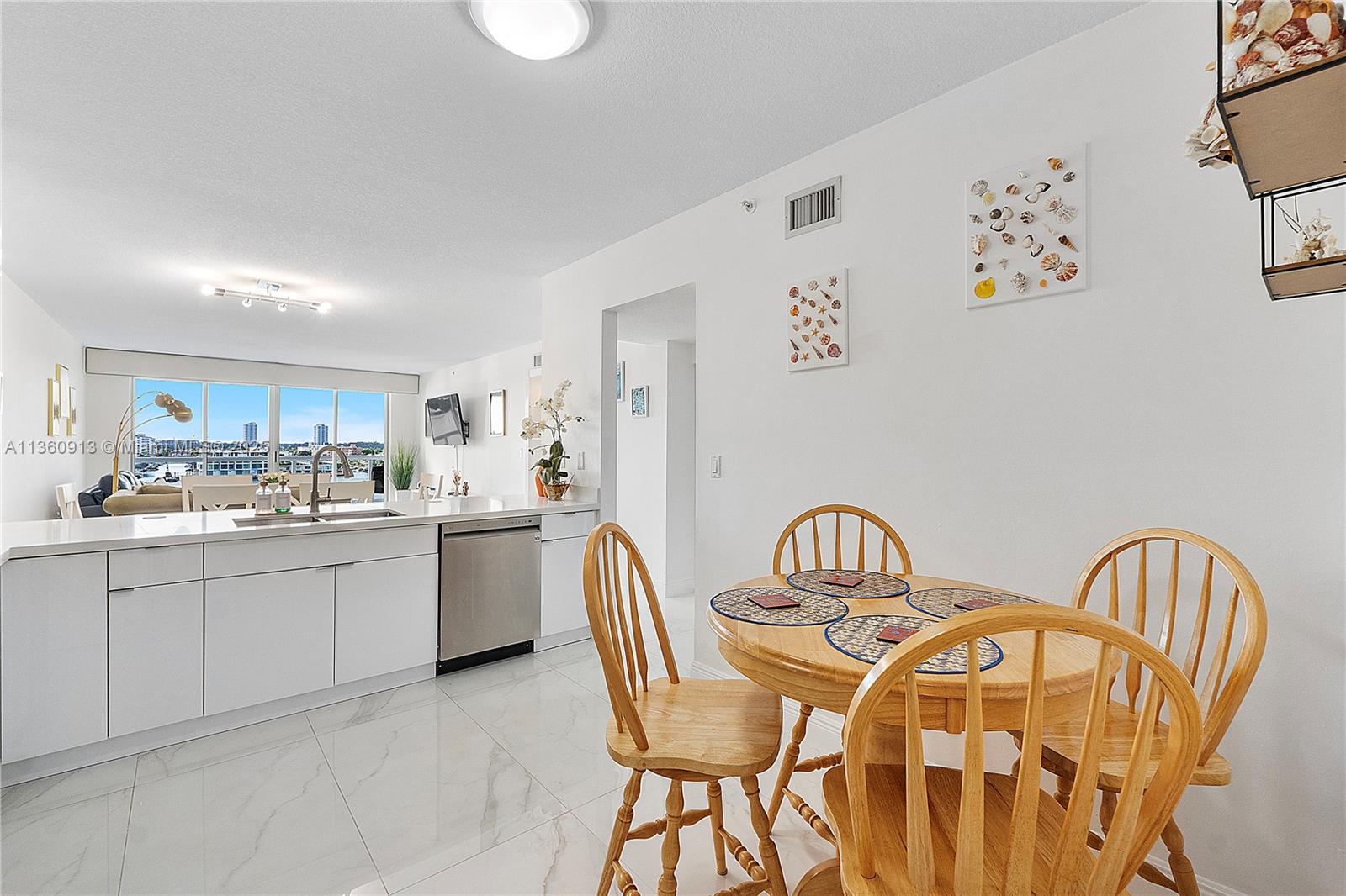 17050 North Bay Road, Unit 807 Sunny Isles Beach, FL 33160 - Photo 8 of 50 a kitchen with stainless steel appliances a sink a table and chair