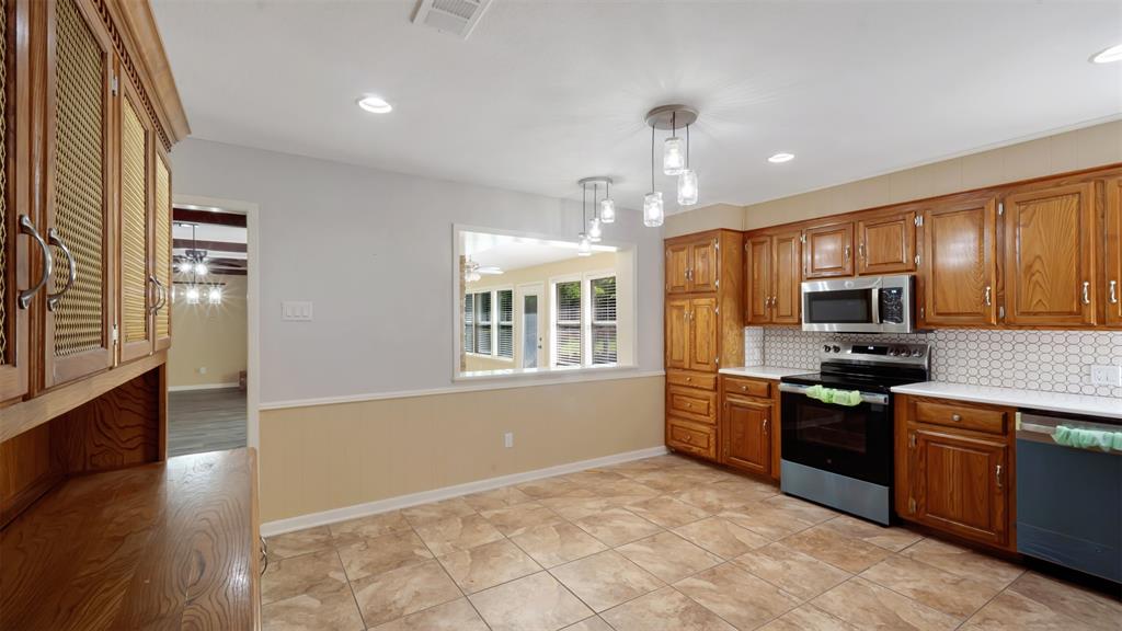 2801 Florence Street Kilgore, TX 75662 - Photo 22 of 39 a kitchen with stainless steel appliances granite countertop a stove top oven a sink dishwasher a dining table and chairs with wooden floor