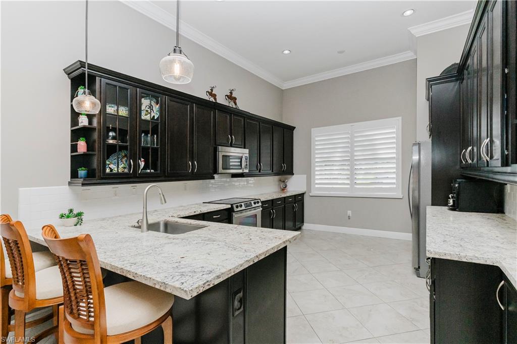 5265 Messina Street Ave Maria, FL 34142 - Photo 3 of 30 a kitchen with granite countertop a stove a sink and a refrigerator
