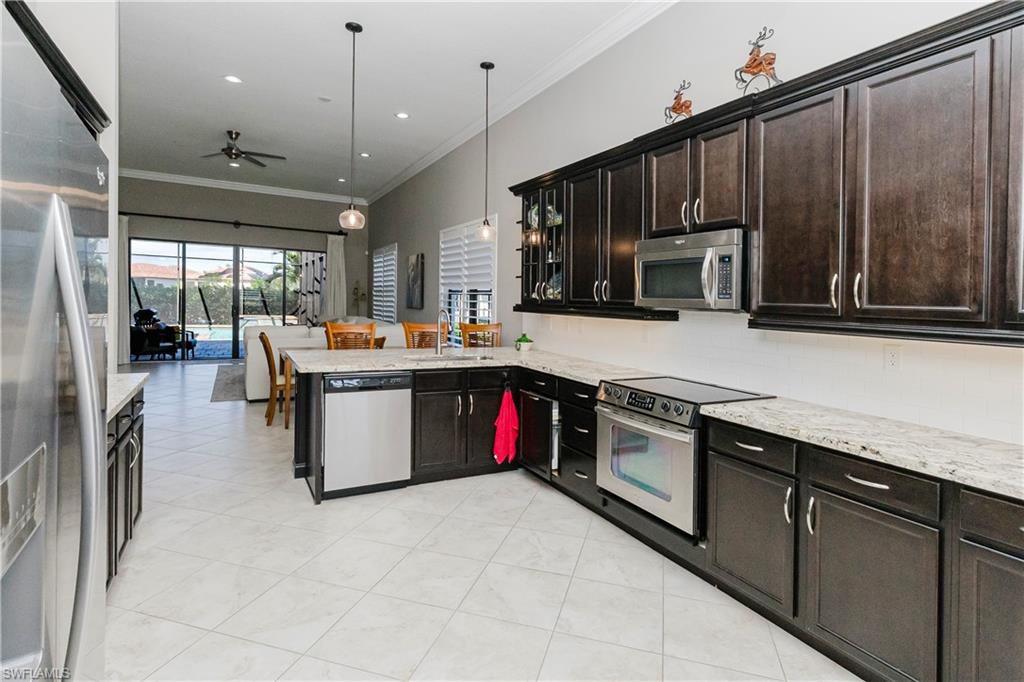 5265 Messina Street Ave Maria, FL 34142 - Photo 7 of 30 a kitchen with stainless steel appliances granite countertop a stove a sink dishwasher a microwave oven and a refrigerator with wooden cabinets