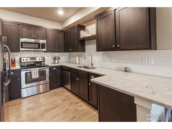 a kitchen with stainless steel appliances granite countertop a sink stove microwave and refrigerator