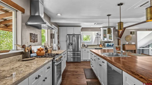 a kitchen with stainless steel appliances granite countertop a sink a stove and a wooden floors