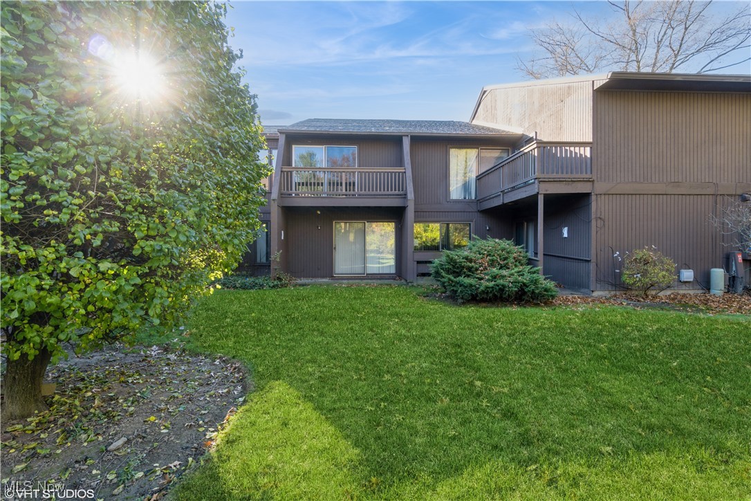 Rear view of house with a yard and a balcony