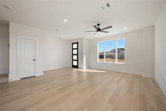 a view of an empty room with a window and wooden floor