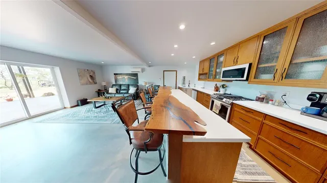 a open kitchen with stainless steel appliances granite countertop a stove top oven a sink a dining table and chairs with wooden floor