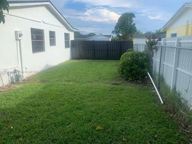 a backyard of a house with plants and wooden fence