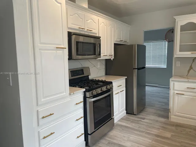 a kitchen with white cabinets and stainless steel appliances