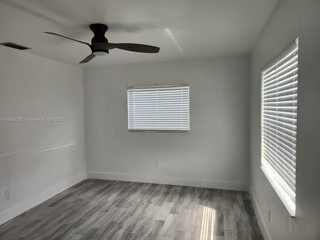 a view of empty room with wooden floor and fan