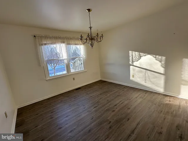 an empty room with wooden floor windows and chandelier