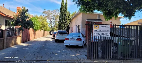 a view of a house with a cars park side of a road