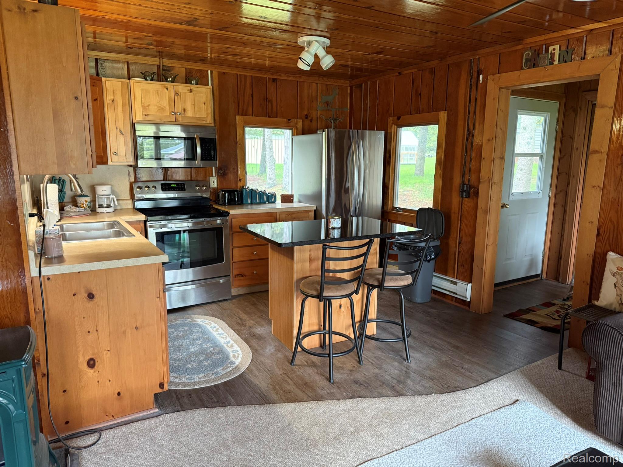 4348 Shrew Road Lincoln, MI 48742 - Photo 8 of 17 Functional kitchen featuring wood-finish cabinetry, stainless steel appliances, and a central island with a dark countertop