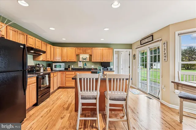 a kitchen with stainless steel appliances granite countertop a refrigerator a stove top oven and a sink with cabinets