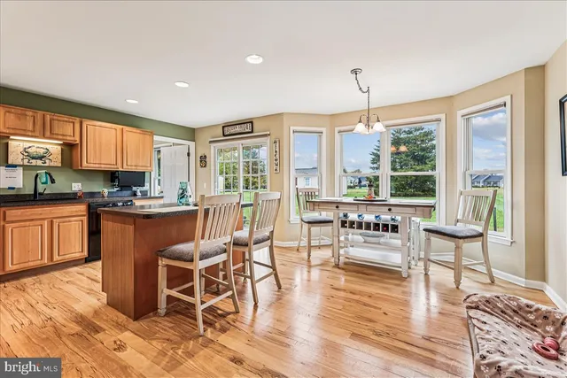 a kitchen with stainless steel appliances granite countertop a refrigerator a stove top oven and a dining table with wooden floor