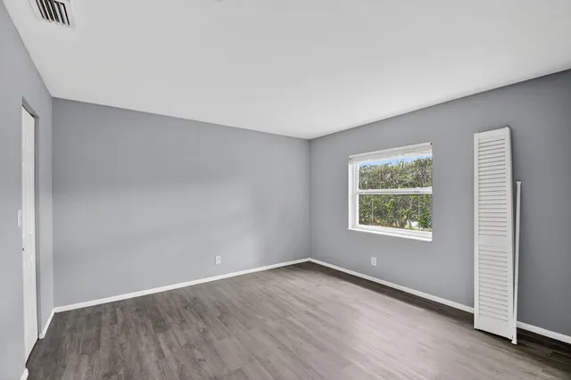 an empty room with wooden floor and windows