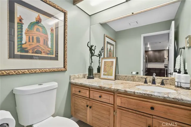 a bathroom with a granite countertop toilet sink and mirror