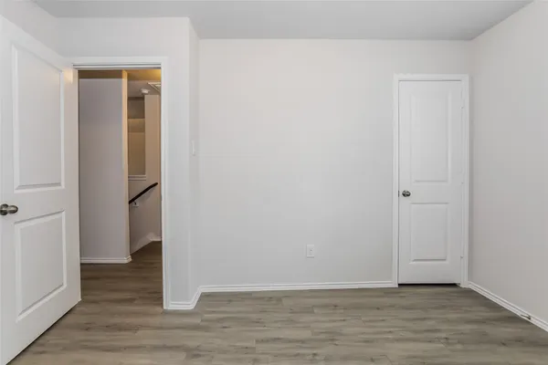 a view of an empty room with wooden floor and closet