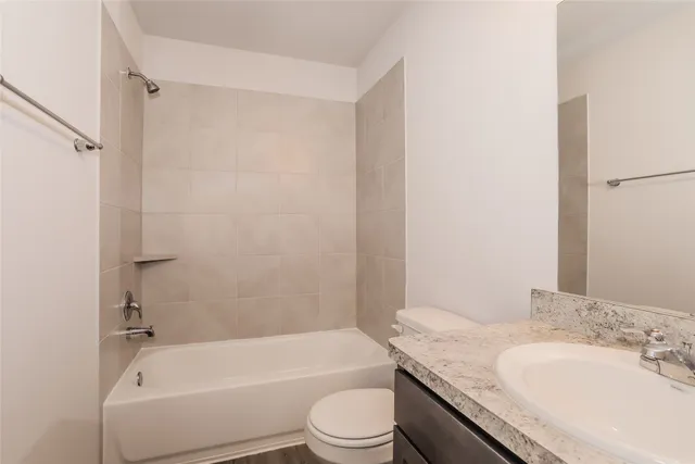 a bathroom with a granite countertop bathtub shower sink vanity mirror and toilet