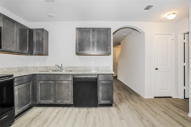 a kitchen with stainless steel appliances granite countertop a sink and wooden floor