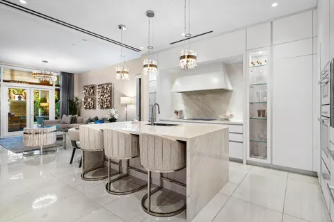 a large kitchen with a sink a counter top space and living room view