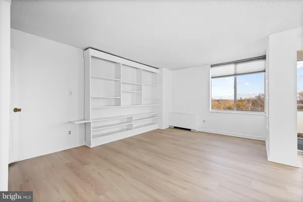 a view of empty room with wooden floor and closet
