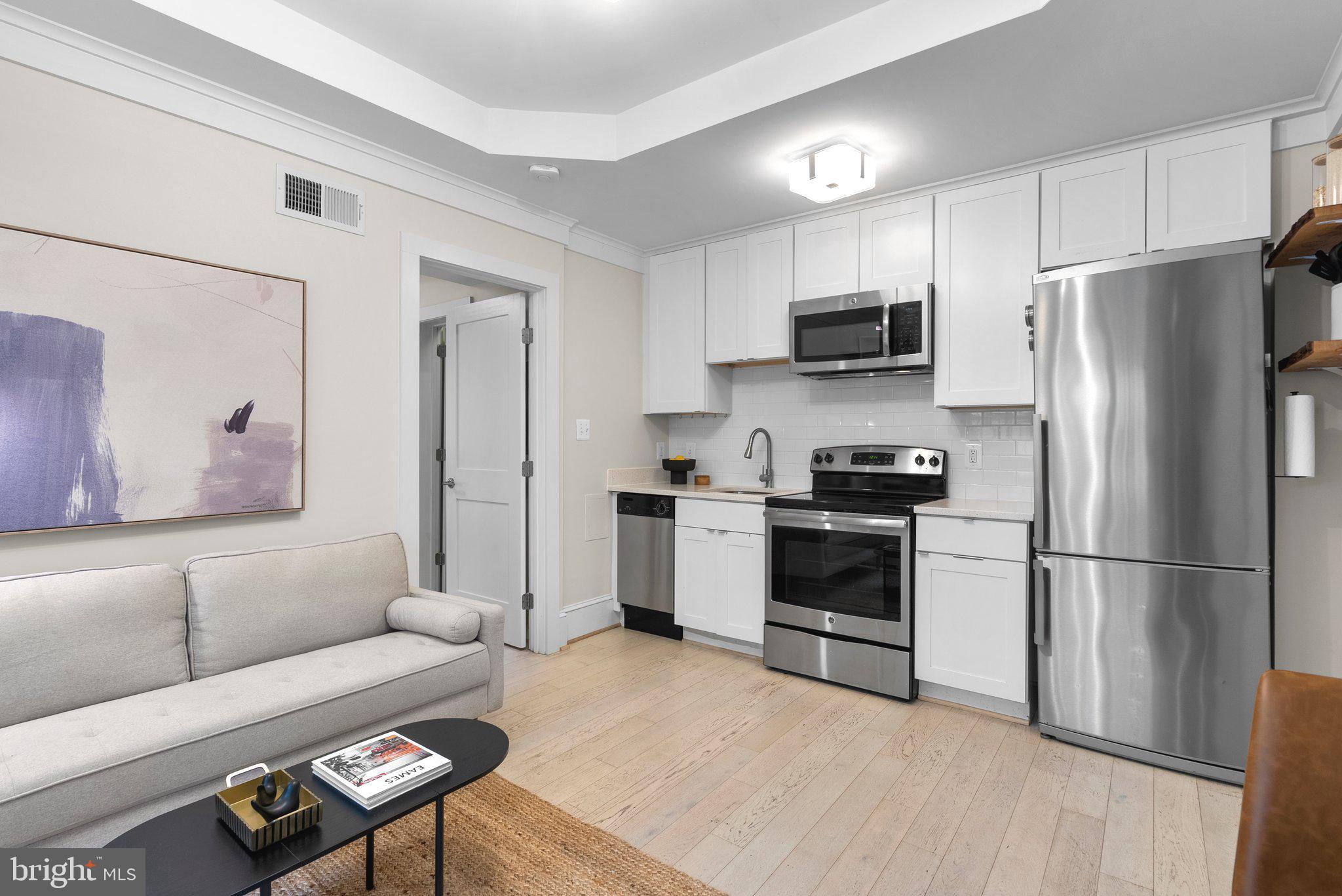 1451 Park Road Northwest, Unit 104 Washington, DC 20010 - Photo 7 of 28 a kitchen with a refrigerator a stove top oven a sink and cabinets