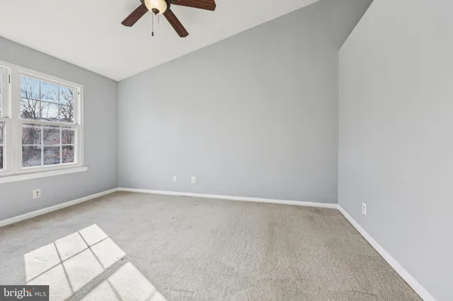 an empty room with windows and ceiling fan
