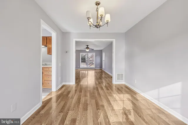 a view of a hallway view with wooden floor and chandelier